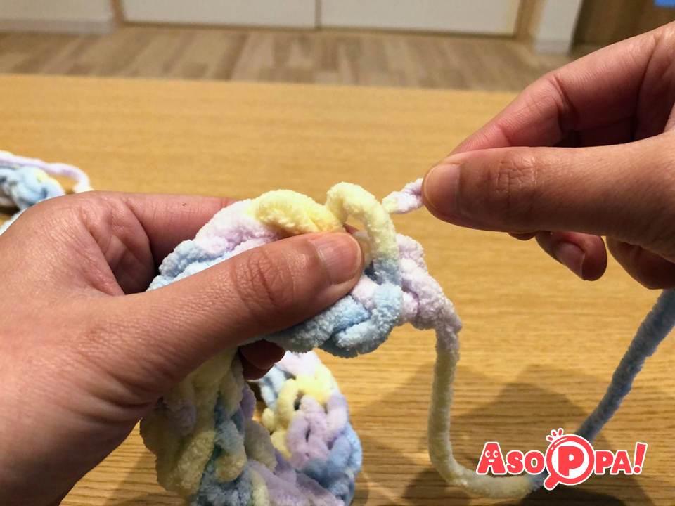 毛糸をマフラーの端の方の編み目に通して、結びます。
編み始めの親指に掛けていた毛糸も同じように結んでおきましょう。