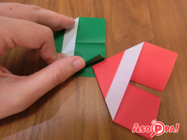 写真のようにパーツ（緑）の四角い部分を１枚めくり、次のパーツ（赤）の三角の部分を差し込みます。