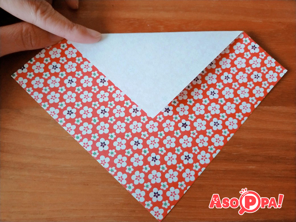 千代紙（折り紙の赤や金でもよい）を写真のように折り、白い逆三角を作ります。