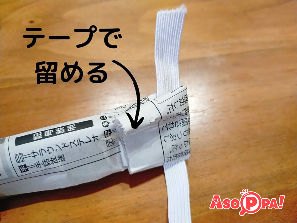 丸めた新聞紙の端に平ゴムを乗せて折りたたみ、セロテープで簡単に留めます。